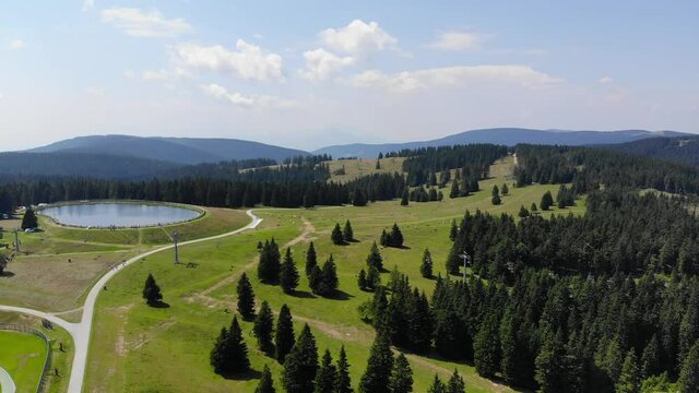 Forest trails in Rogla sports resort Slovenia during springtime passing around a lake, Aerial flyover shot