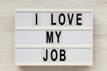 'I love my job' on a modern board on a white wooden background, top view. Flat lay, from above, overhead. Close-up.
