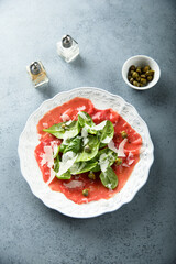 Homemade beef carpaccio with arugula and cheese