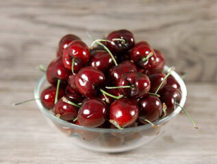 Cup of ripe cherries on a wooden background