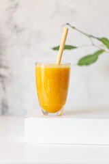 Tasty peach smoothie in glass on white table