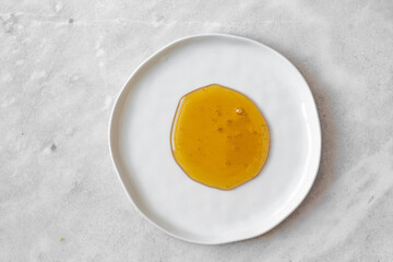  honey drops in white plate on mable background