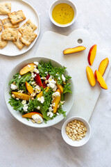 Autumn salad of iceberg lettuce, spinach, peach and goat cheese in a white rustic plate on marble background with copy space