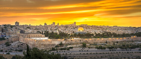 Fototapeta premium Beautiful panoramic view of Jerusalem - Old and New City, with the Dome of the Rock and the Temple Mount, south-east wall corner with Hulda Gates archaeological site and dramatic orange sunset sky
