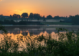morning landscape with lake, green grass in the foreground, sunrise on the lake, summer