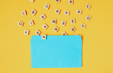 wooden English letters fly out of a blue envelope on a yellow wooden background