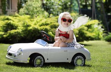 Toddler sitting in a toy car in backyard
