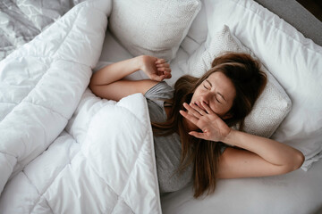 Young beautiful woman enjoying in morning.. Girl lying on bed.	