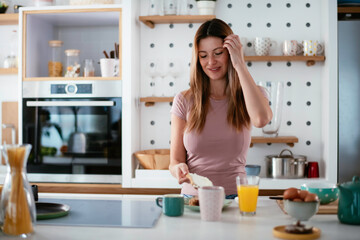 Young woman in kitchen. Beautiful woman preparing breakfast and drinking coffee.	