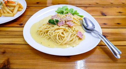 The spaghetti, fried cheese in a white plate on a wooden table.