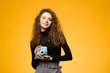 Beautiful girl with photo camera isolated on yellow background