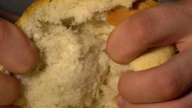 Caucasian man baker breaks bread into two parts. Close-up macro of a breaking bread.