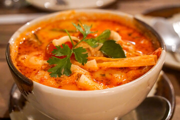 Tom Yam shrimp soup, large. Orange in a white soup plate. Traditional thai food