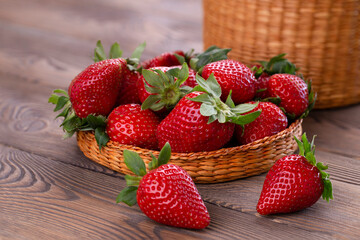 Organic juicy strawberries in a wicker bowl on a brown shabby wooden table, place for text