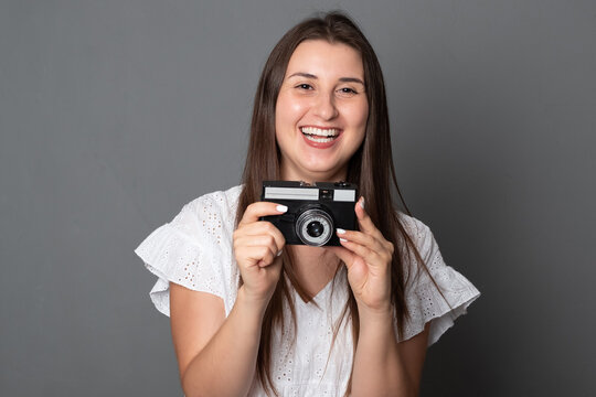 Smiling woman takes pictures with an old camera. Beautiful girl holds a camera.