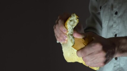 Caucasian man baker breaks white bread into two parts. Close-up of a breaking bread.