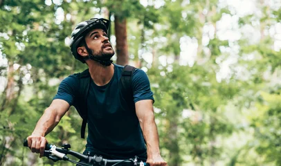 Fotobehang Outdoor image of handsome cyclist man riding bike in the mountain. Male athlete in cycling gear practising outside in the forest on nature background. Travel and extreme sport concept. © iuricazac