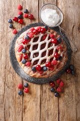 Tasty summer Berry pie with raspberries, blueberries and cherries close-up on a slate board on the table. vertical top view from above