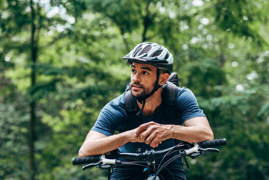 Biker man resting during riding the bike in the mountain. Male athlete in cycling gear practising outside on nature background. Travel and extreme sport concept.