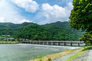 Fototapeta premium Togetsukyo Bridge in Arashiyama, Kyoto, Japan. vivid fresh greenery in early summer and the Katsuragawa river flowing vigorously.