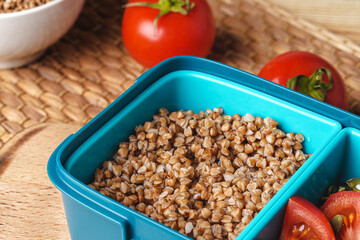 Blue lunch box with buckwheat and tomatoes
