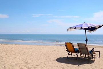 Bed beach and blue umbrella on tropical beach with blue sky in the summer morning. Nature and travel concept.