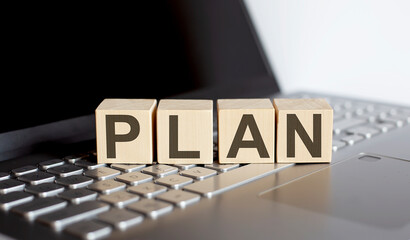 wooden blocks with PLAN text of concept on laptop