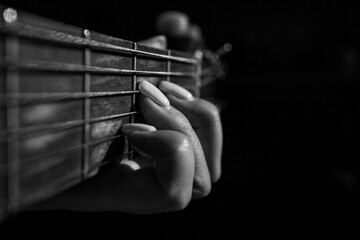 Close-Up Of hand guitar player. Acoustic guitarist women hands. Musician's fingers on the strings of an Acoustic guitar in black and white. Chord in female hands.