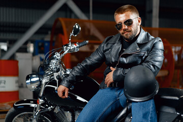 Fototapeta na wymiar Portrait of bearded man motocyclist in dark sunglasses on dark background