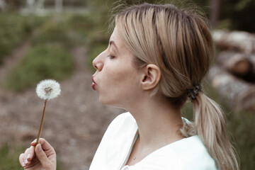 girl is blows away dandelion blowball