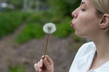 girl is blows away dandelion blowball