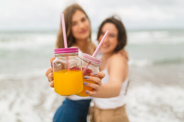 Friends toast by the sea on the beach on a sunny summer day. You raise your arms and they have...