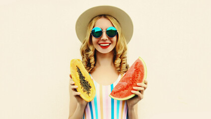 Obraz premium Summer portrait of happy smiling woman with fruits slice of watermelon and papaya wearing straw hat, sunglasses on white background