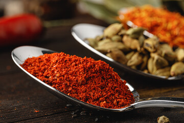 Spoon with spices on dark wooden table close up
