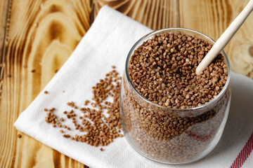 Bowl of raw uncooked buckwheat on wooden table