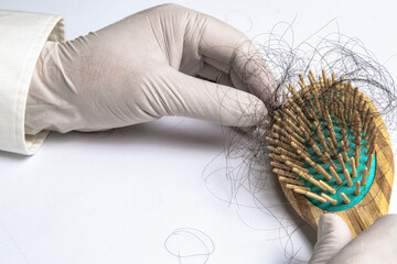 Hair loss experts wear gloves pick up hair from brush for examination. On a white background with copy space on right.