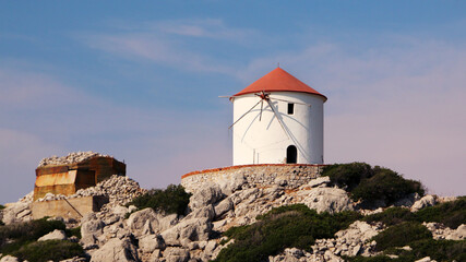 Fototapeta na wymiar Windmill on the shore, Symi island, Panormitis, Greece