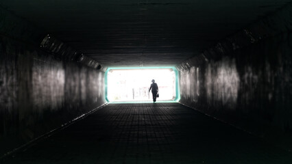 Silhouette of woman in dark underpass. Danger of loneliness and insecurity in city