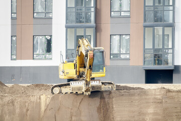 Construction of an apartment building. The excavator performs work on the planning territory and...