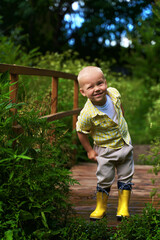 a little boy in yellow boots and a yellow shirt winks