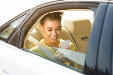 Black Young Lady Using Smartphone Browsing Internet Sitting In Car