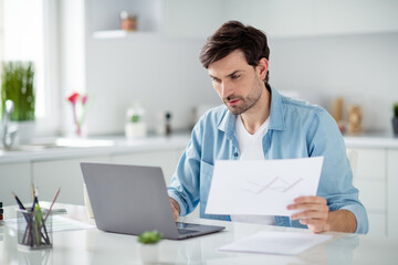 Photo of handsome serious boss guy businessman browsing notebook sitting table read contract check papers work stay home online lesson education webinar skilled teacher quarantine indoors