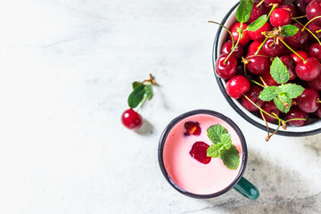 Yogurt with cherry, mint and and fresg berries on a light concrete background. Summer healthy dessert with berries.