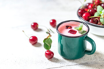 Yogurt with cherry, mint and and fresg berries on a light concrete background. Summer healthy dessert with berries.