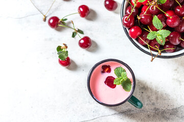 Yogurt with cherry, mint and and fresg berries on a light concrete background. Summer healthy dessert with berries.