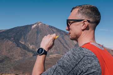 Portrait of young man eat sports nutrition energy gel while sitting and resting after trail running