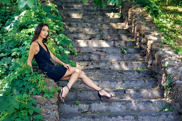 Young beautiful girl of Eastern appearance in the city .The model wears a short black dress