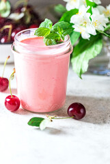 Yogurt with cherry, mint and and fresg berries on a light concrete background. Summer healthy dessert with berries.