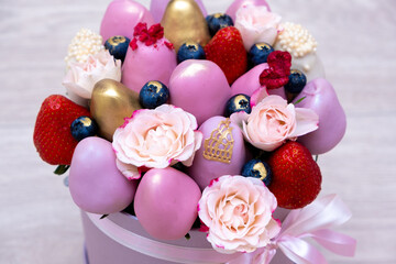 Fresh strawberries in pink, gold and white chocolate with pink flowers in the form of a fruit bouquet.