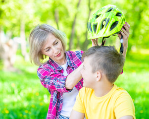 Mother put on helmet to her son for a safe ride on a bike